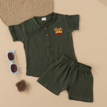 Dark olive green boys muslin co-ord with giraffe patch embroidery, round neck shirt with buttons, and elastic shorts – by Boon Babies, Coimbatore.
