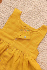 Baby girl wearing a yellow sleeveless solid muslin frock by Boon Babies, featuring four layers for a playful, elegant look.
