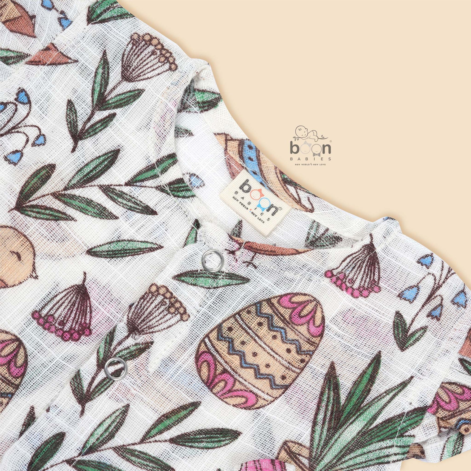 Cotton baby romper with colorful botanical and bird print, flutter sleeves, side bows, and front snap buttons – from Boon Babies, Coimbatore.
