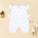 White muslin baby romper with tiny red heart prints, featuring frill sleeves, side bows, and front snap buttons – from Boon Babies, Coimbatore.