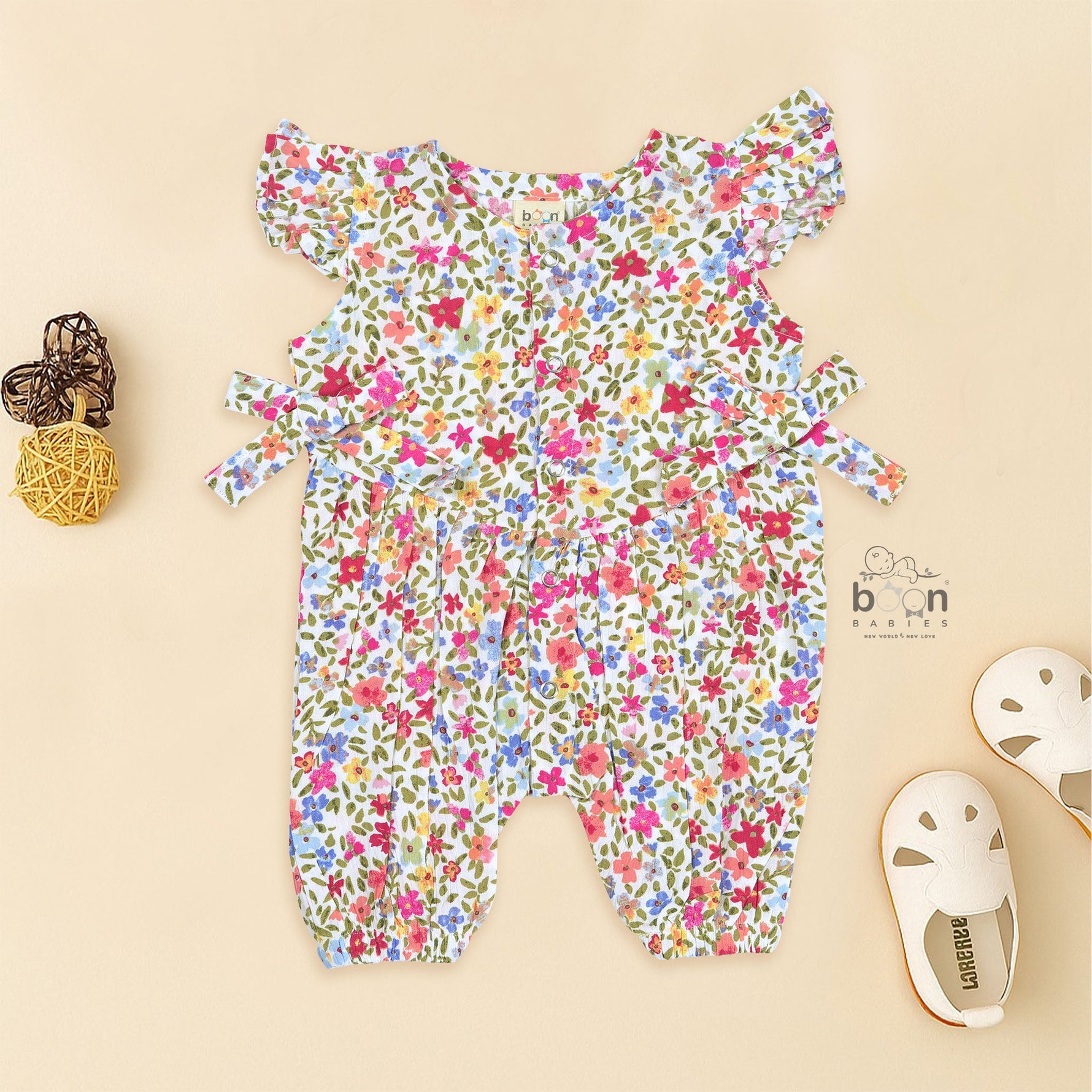 Baby girl romper in soft crinkled muslin with multicolor floral print, flutter sleeves, and side bows – ideal for babies aged 0–12 months by Boon Babies, Coimbatore.