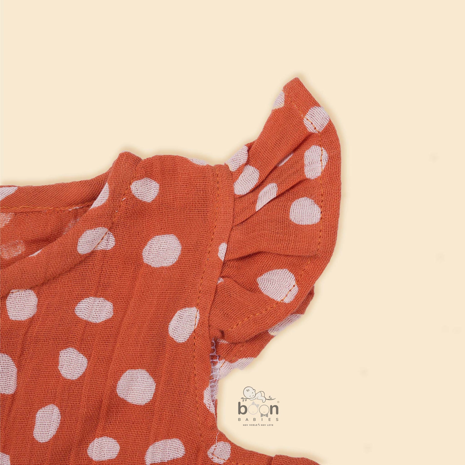 Rust orange baby romper with white polka dots, flutter sleeves, and side bows – made from soft crinkled muslin for babies aged 0–12 months by Boon Babies, Coimbatore.