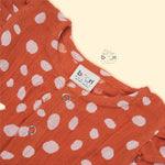Rust orange baby romper with white polka dots, flutter sleeves, and side bows – made from soft crinkled muslin for babies aged 0–12 months by Boon Babies, Coimbatore.