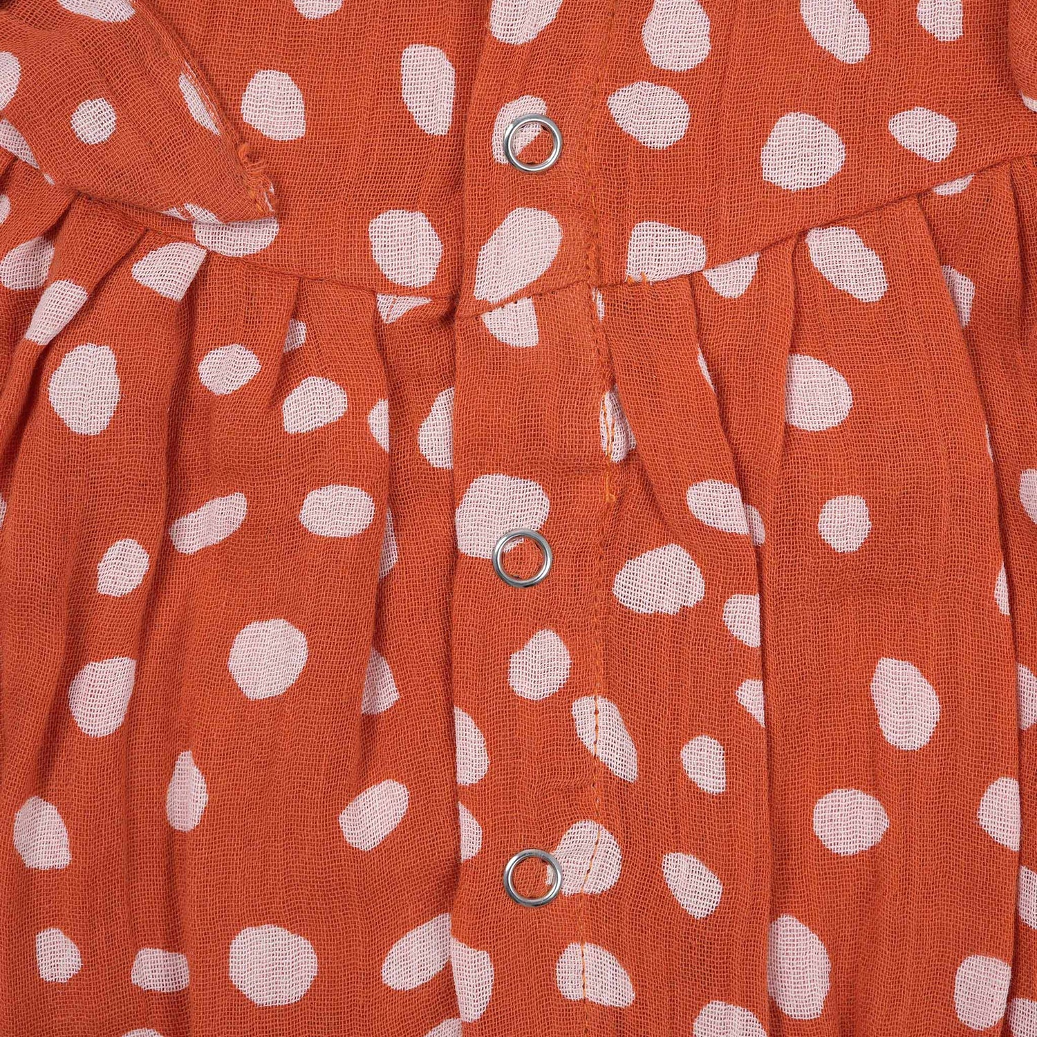 Rust orange baby romper with white polka dots, flutter sleeves, and side bows – made from soft crinkled muslin for babies aged 0–12 months by Boon Babies, Coimbatore.