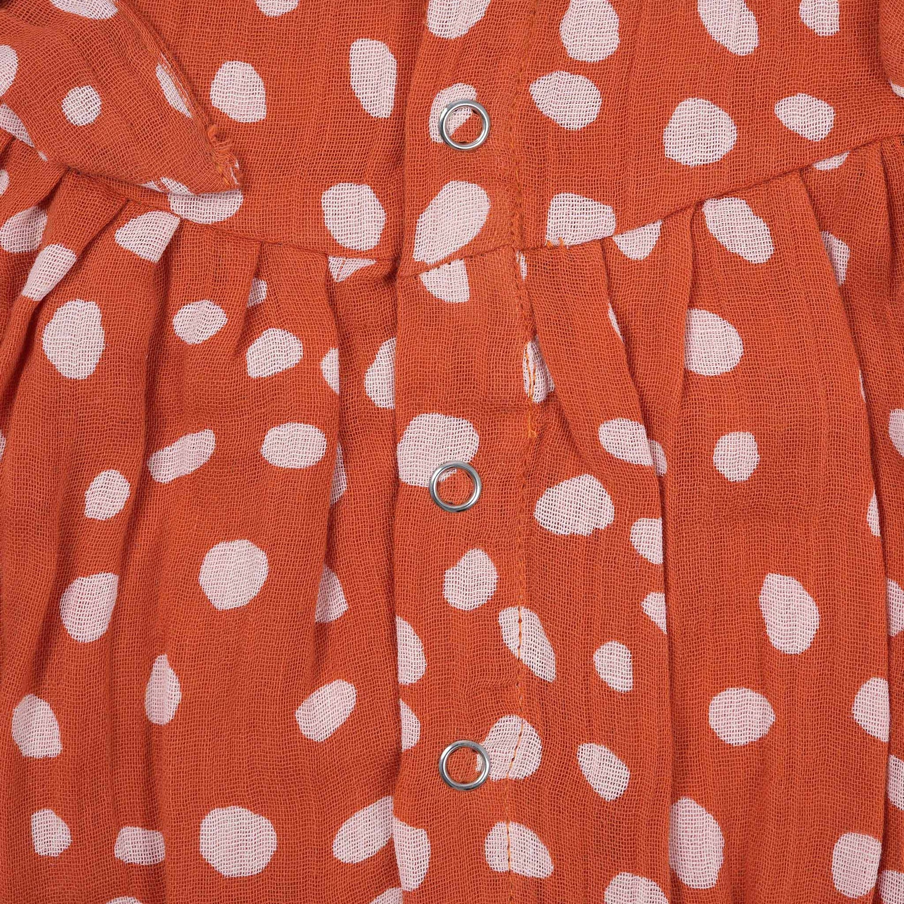 Rust orange baby romper with white polka dots, flutter sleeves, and side bows – made from soft crinkled muslin for babies aged 0–12 months by Boon Babies, Coimbatore.