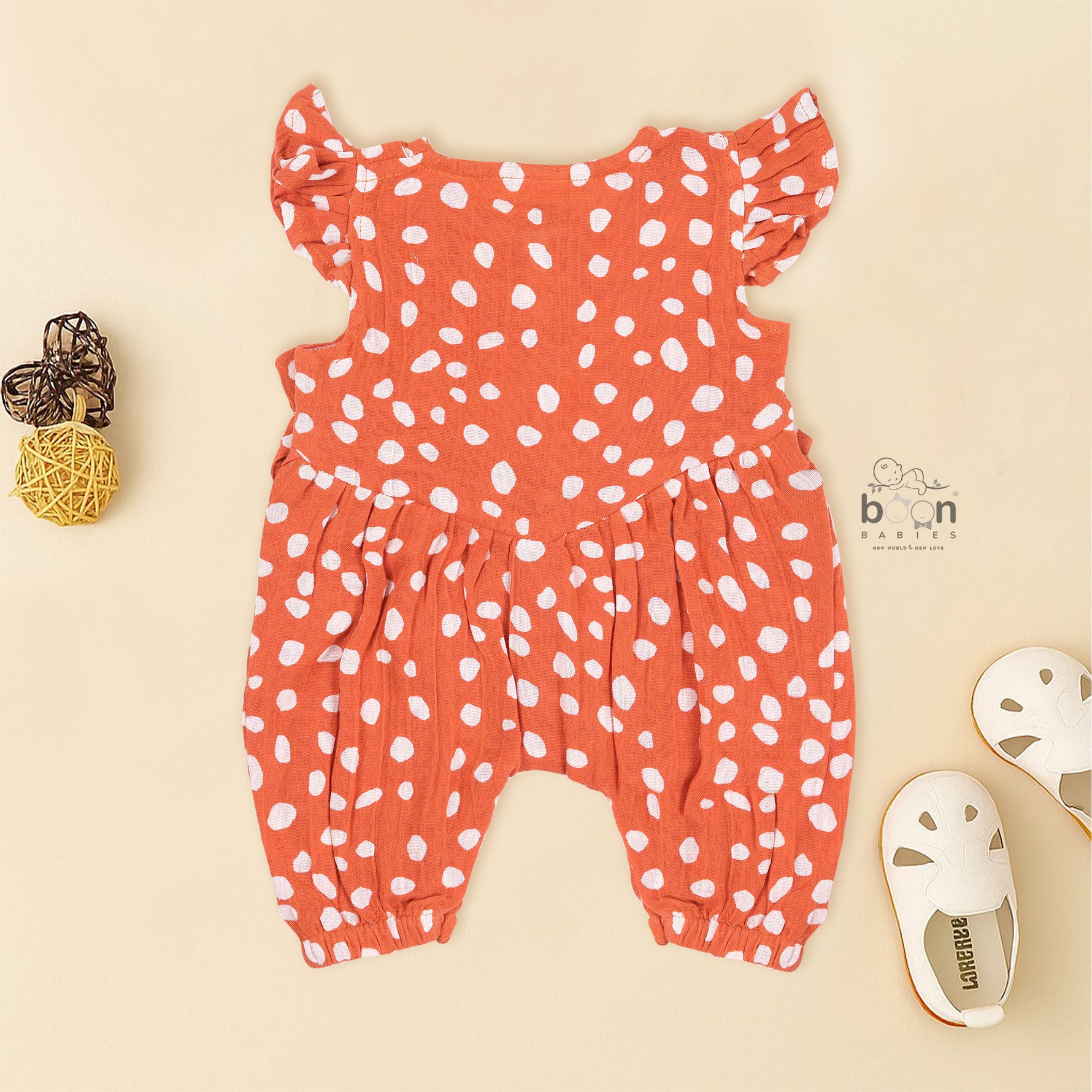 Rust orange baby romper with white polka dots, flutter sleeves, and side bows – made from soft crinkled muslin for babies aged 0–12 months by Boon Babies, Coimbatore.