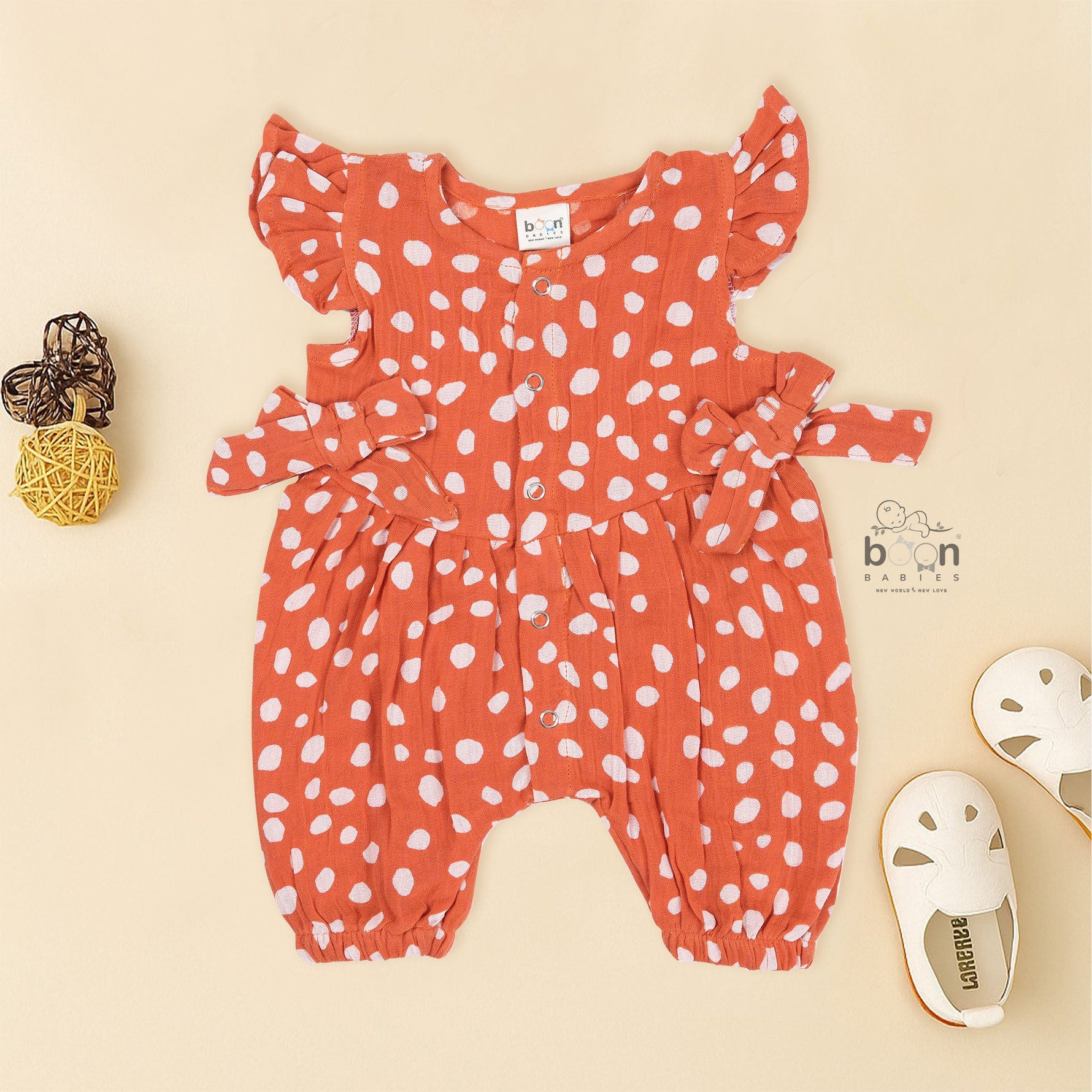Rust orange baby romper with white polka dots, flutter sleeves, and side bows – made from soft crinkled muslin for babies aged 0–12 months by Boon Babies, Coimbatore.