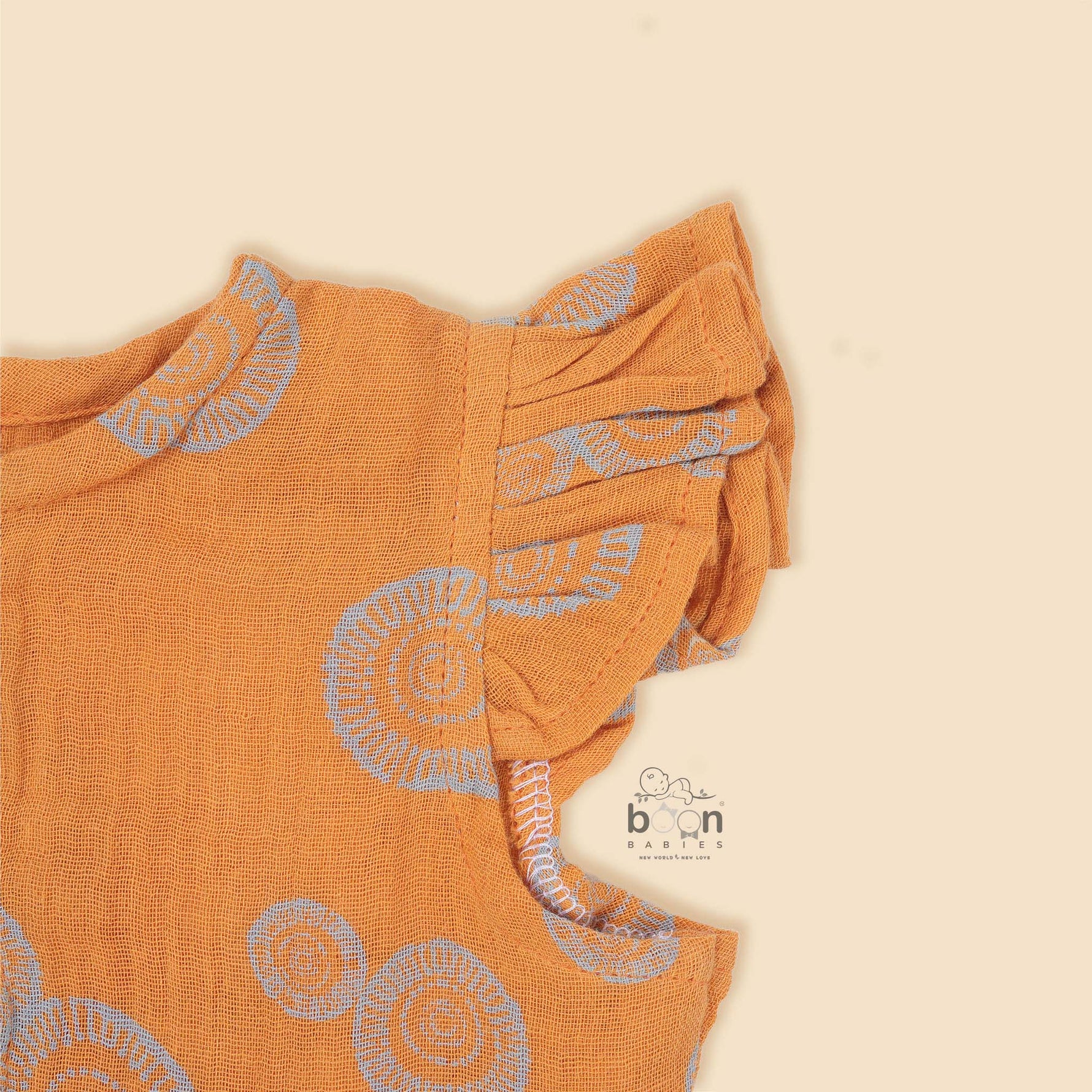 Crinkled muslin baby romper in rust orange with spiral print, flutter sleeves, and snap-down front – soft summer outfit for babies from Boon Babies, Coimbatore.