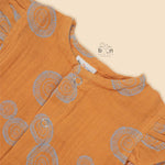 Crinkled muslin baby romper in rust orange with spiral print, flutter sleeves, and snap-down front – soft summer outfit for babies from Boon Babies, Coimbatore.