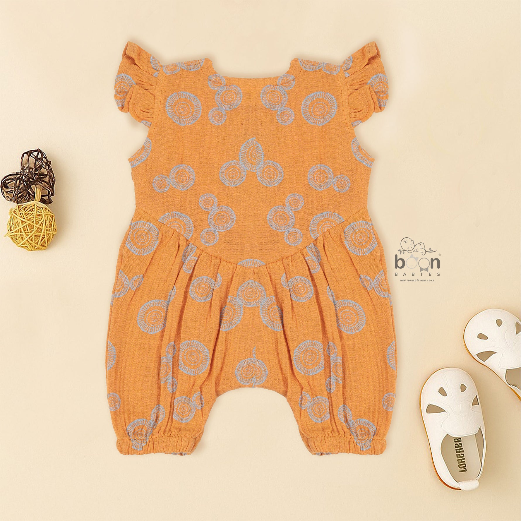 Crinkled muslin baby romper in rust orange with spiral print, flutter sleeves, and snap-down front – soft summer outfit for babies from Boon Babies, Coimbatore.