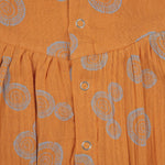 Crinkled muslin baby romper in rust orange with spiral print, flutter sleeves, and snap-down front – soft summer outfit for babies from Boon Babies, Coimbatore.