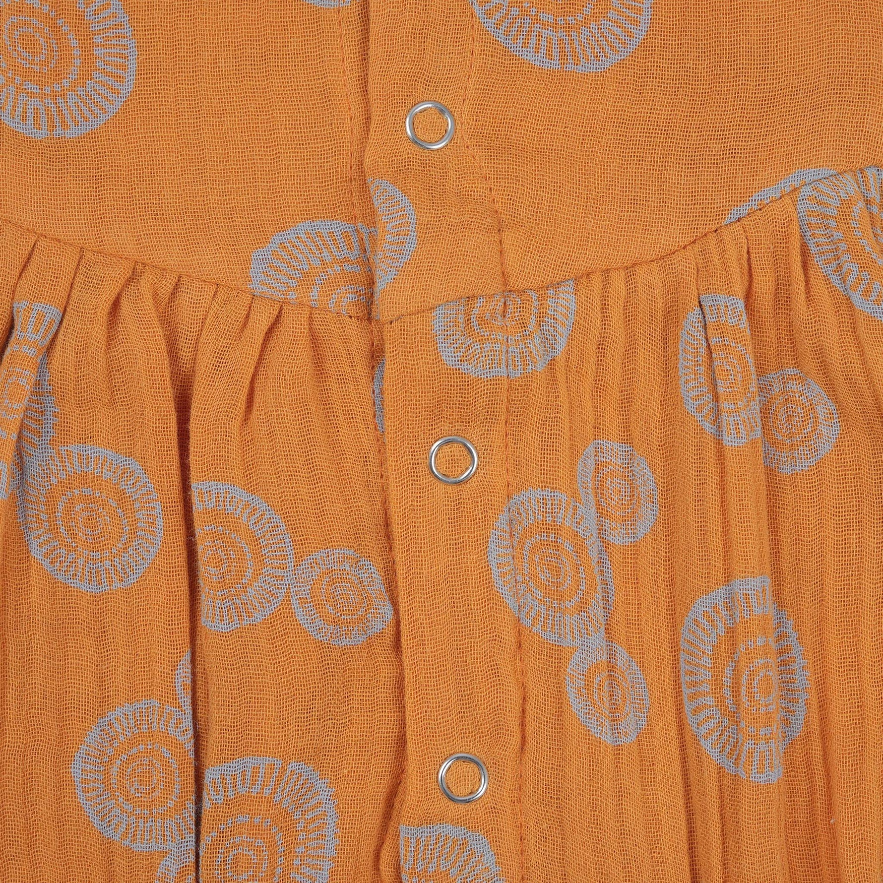 Crinkled muslin baby romper in rust orange with spiral print, flutter sleeves, and snap-down front – soft summer outfit for babies from Boon Babies, Coimbatore.
