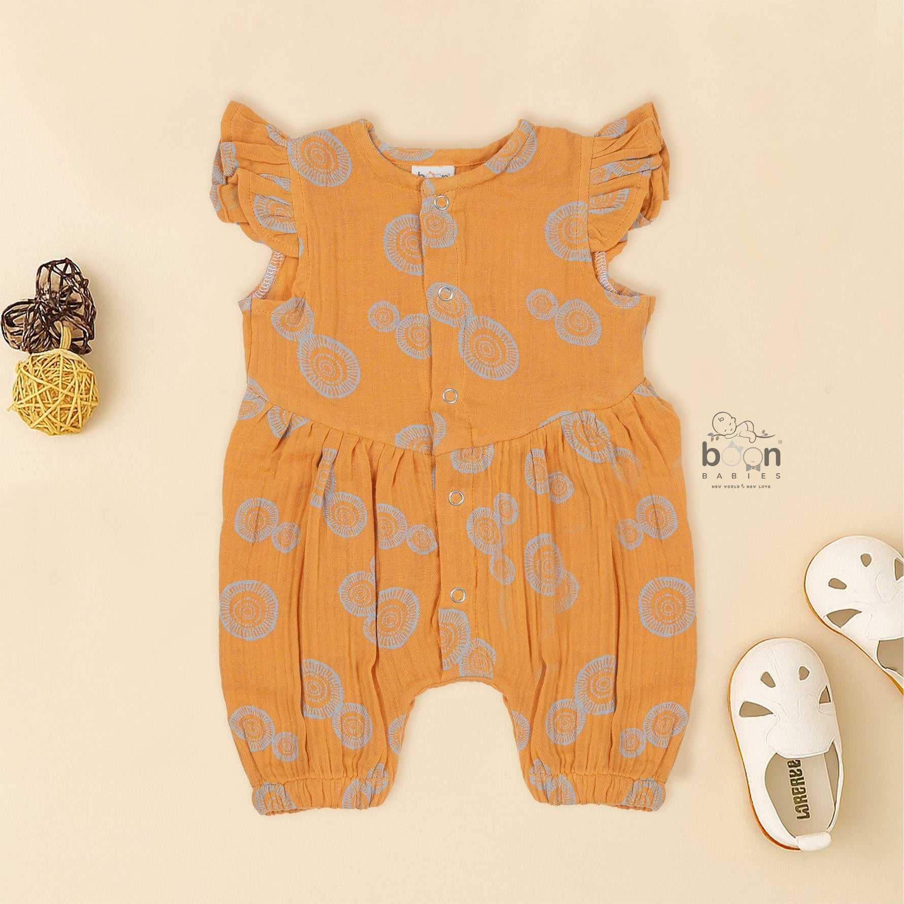 Crinkled muslin baby romper in rust orange with spiral print, flutter sleeves, and snap-down front – soft summer outfit for babies from Boon Babies, Coimbatore.