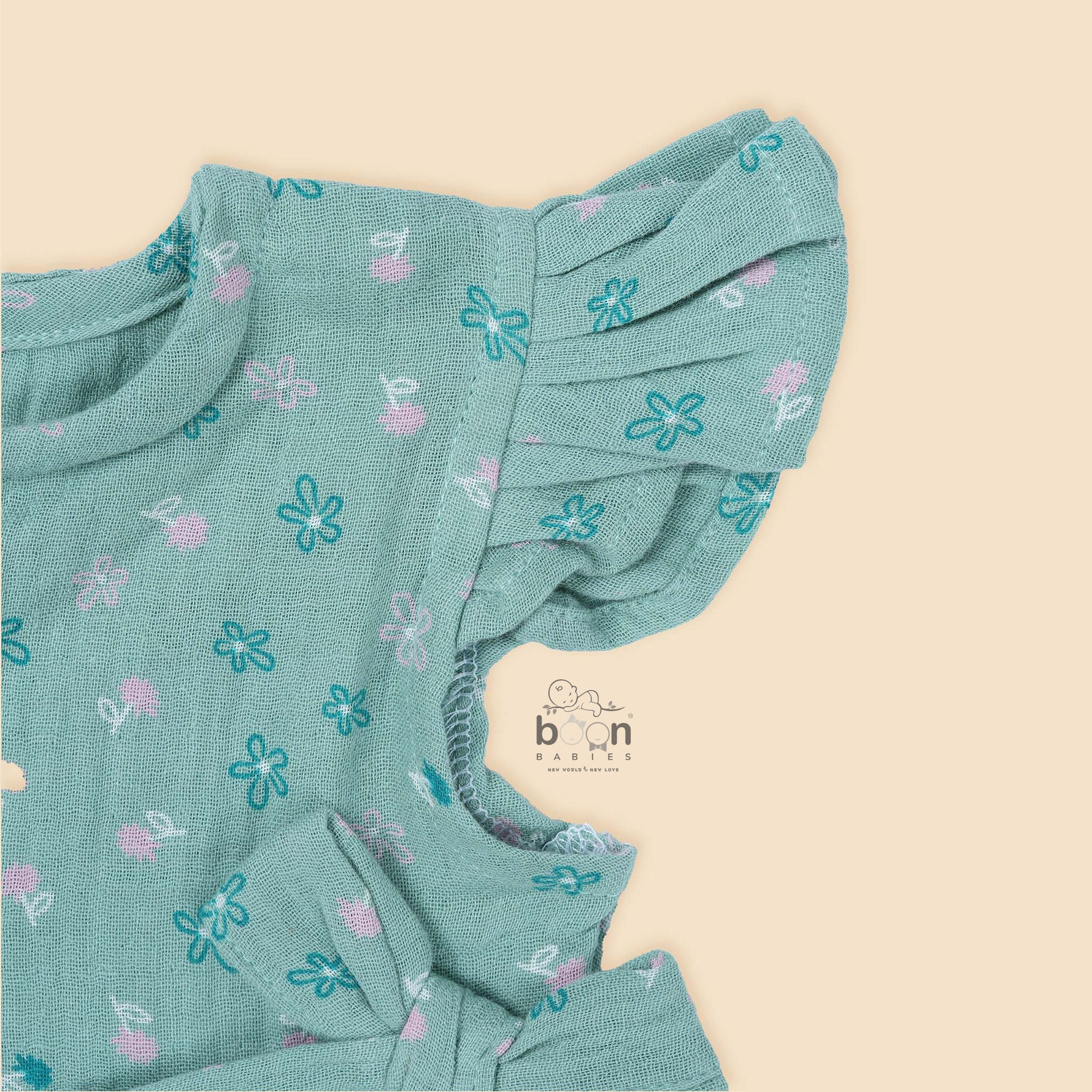 Teal blue baby romper with white floral prints, flutter sleeves, and side bows made from breathable crinkled muslin – designed for babies aged 0–12 months by Boon Babies, Coimbatore.