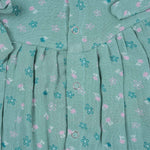 Teal blue baby romper with white floral prints, flutter sleeves, and side bows made from breathable crinkled muslin – designed for babies aged 0–12 months by Boon Babies, Coimbatore.