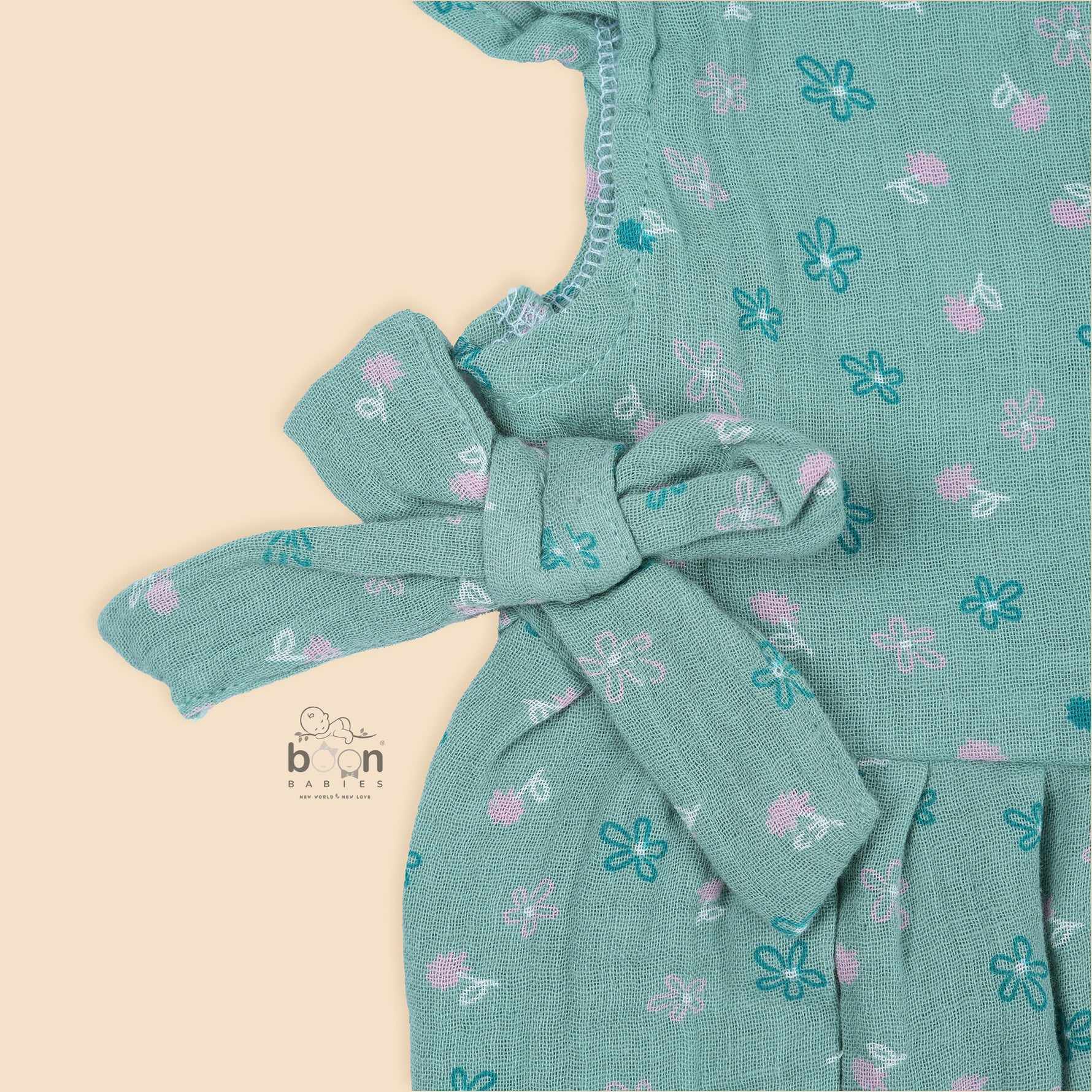 Teal blue baby romper with white floral prints, flutter sleeves, and side bows made from breathable crinkled muslin – designed for babies aged 0–12 months by Boon Babies, Coimbatore.