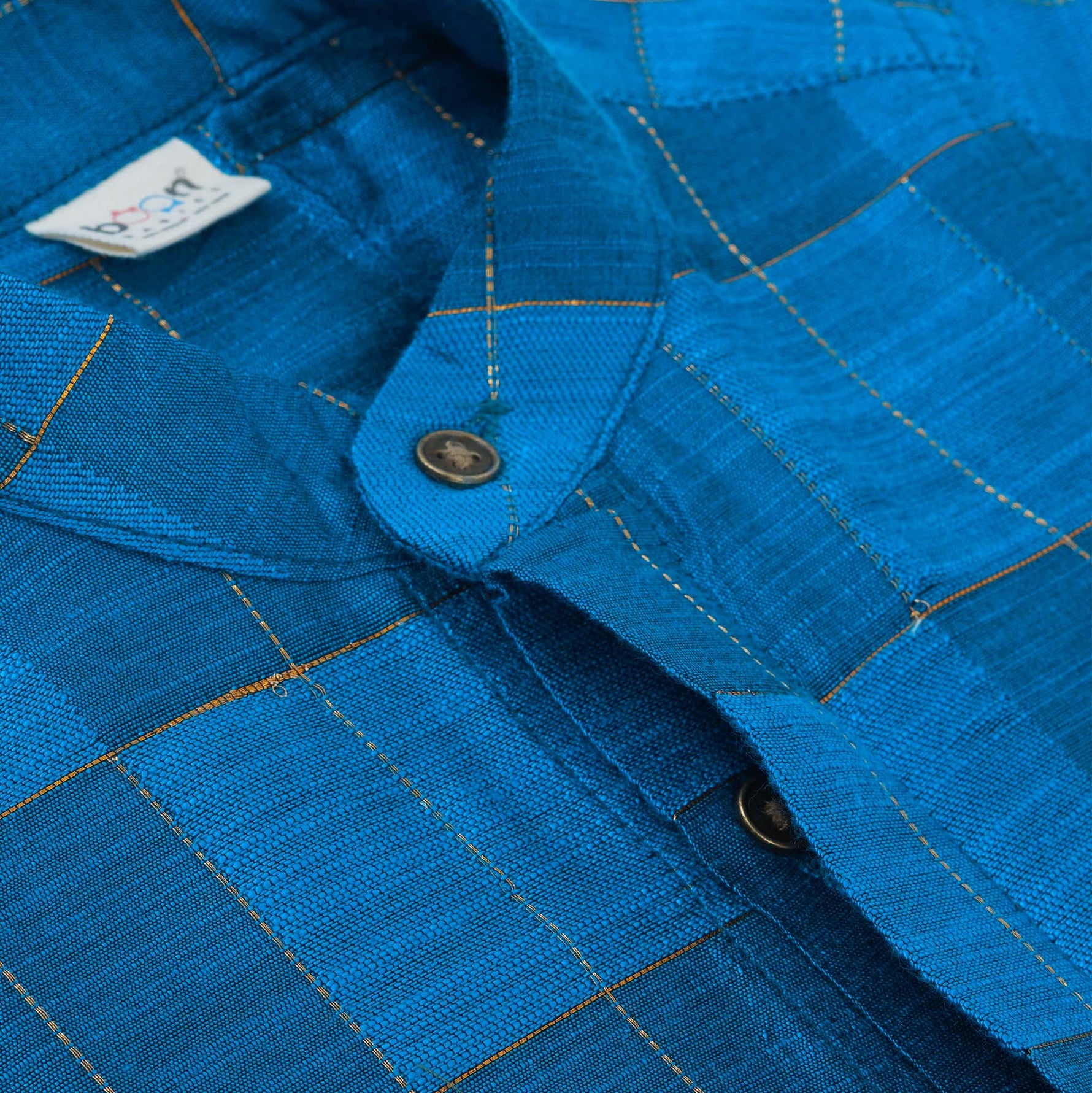 Blue checked silk shirt with Chinese collar and white dhoti with gold border – boys traditional outfit from Boon Babies, styled flatlay.
