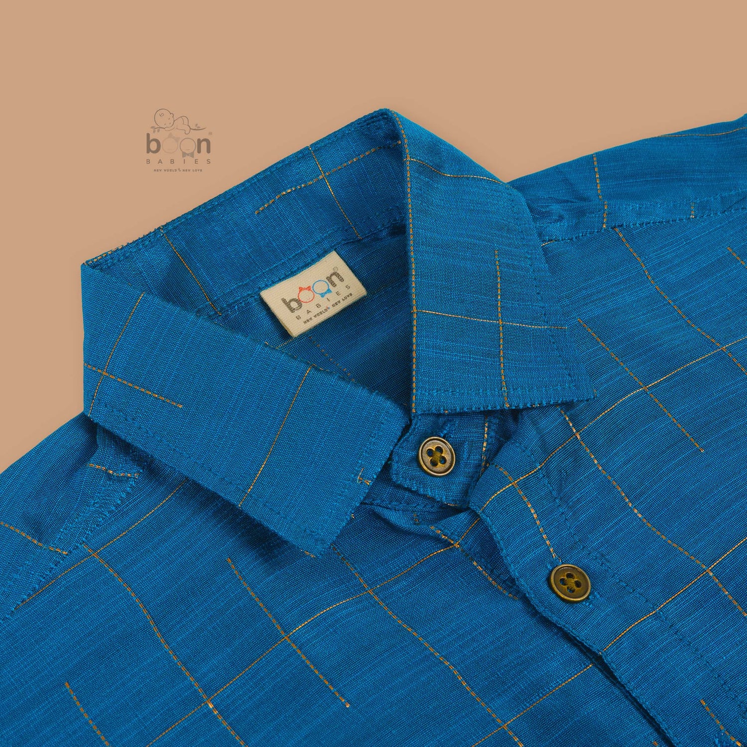 Boys festive outfit featuring a royal blue checked silk shirt and white dhoti with gold border – traditional South Indian attire by Boon Babies.
