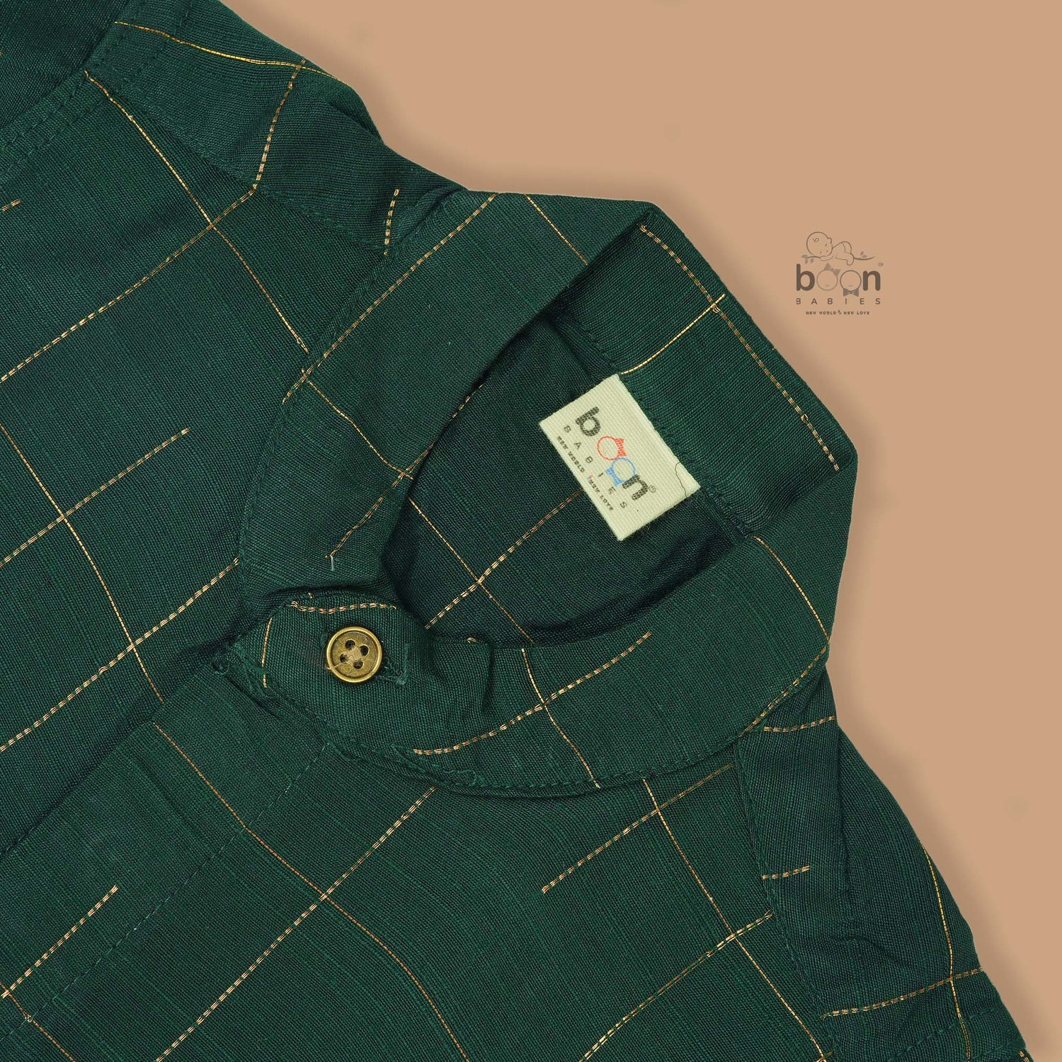 Dark green checked silk Chinese collar shirt with white dhoti and golden border – boys traditional wear flatlay by Boon Babies.
