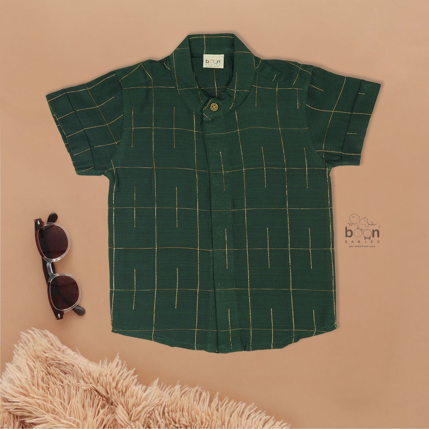Dark green checked silk Chinese collar shirt with white dhoti and golden border – boys traditional wear flatlay by Boon Babies.

