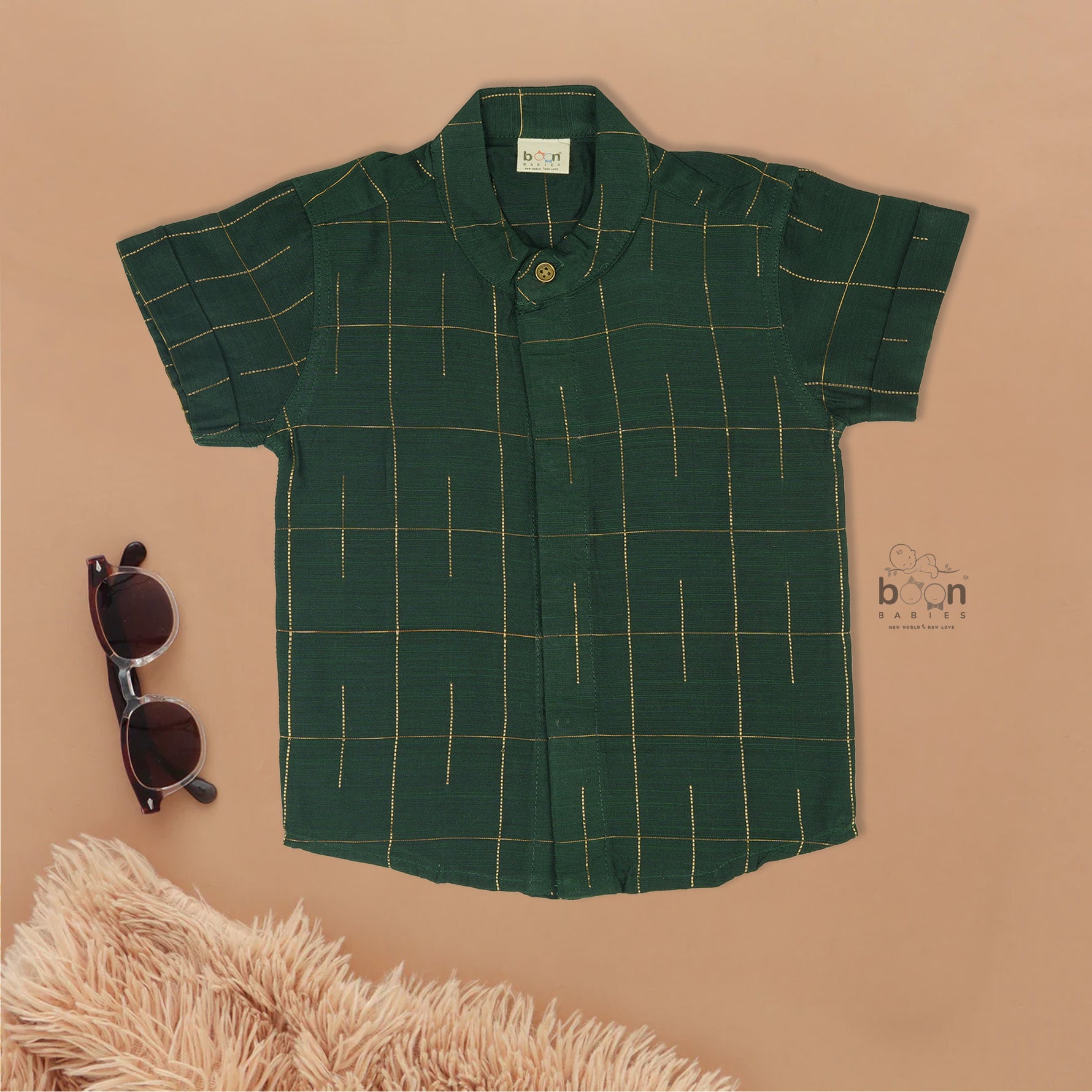 Dark green checked silk Chinese collar shirt with white dhoti and golden border – boys traditional wear flatlay by Boon Babies.

