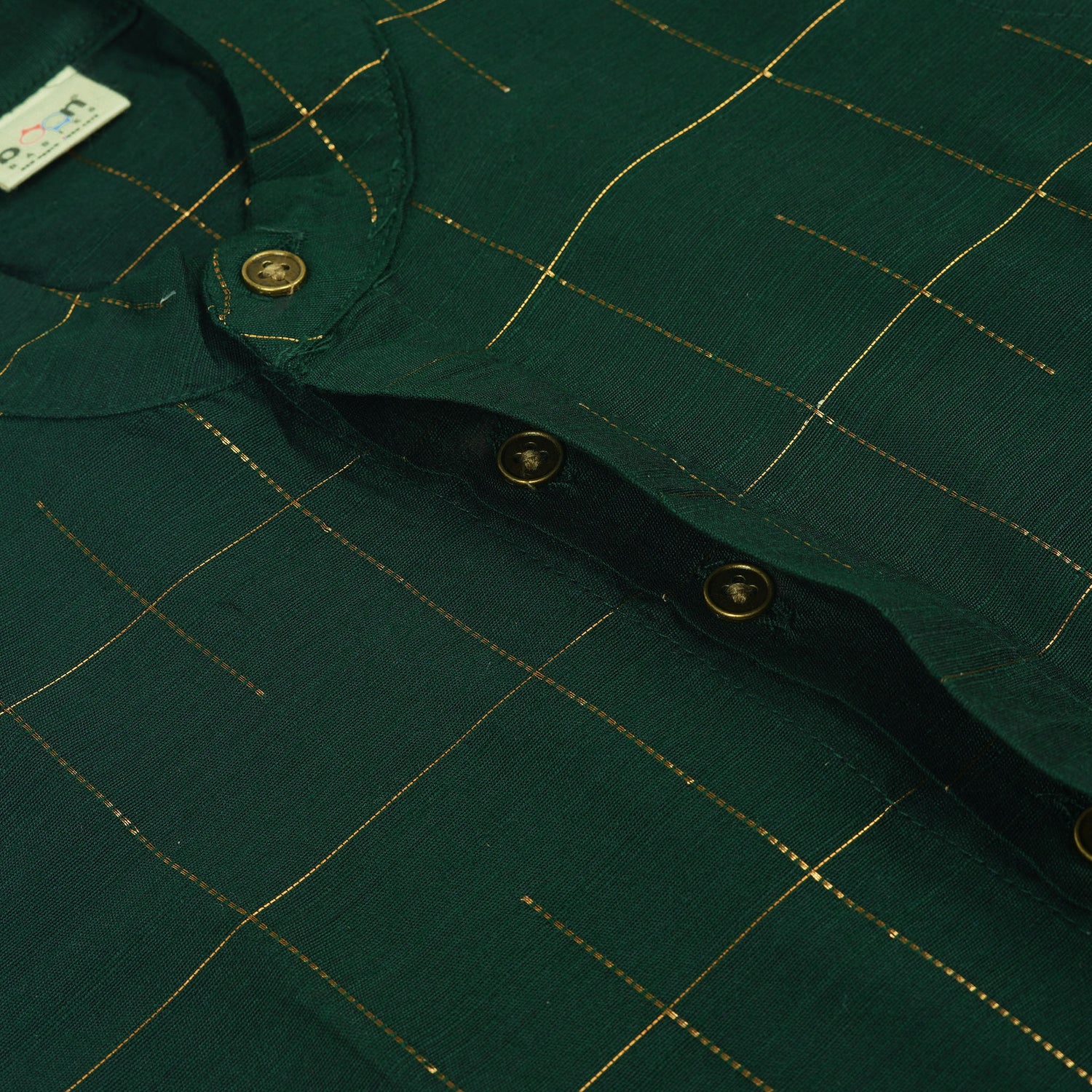 Dark green checked silk Chinese collar shirt with white dhoti and golden border – boys traditional wear flatlay by Boon Babies.
