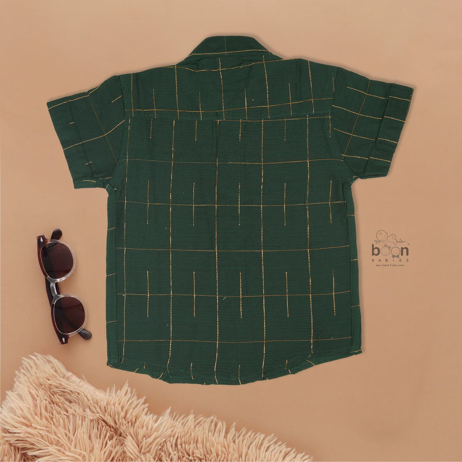Dark green checked silk Chinese collar shirt with white dhoti and golden border – boys traditional wear flatlay by Boon Babies.
