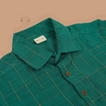 Green silk checked shirt with white dhoti featuring golden border – traditional South Indian boys ethnic wear set by Boon Babies.
