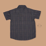 Boys ethnic silk shirt in navy with checked pattern paired with white and gold bordered dhoti, displayed flatlay style – festive wear from Boon Babies.
