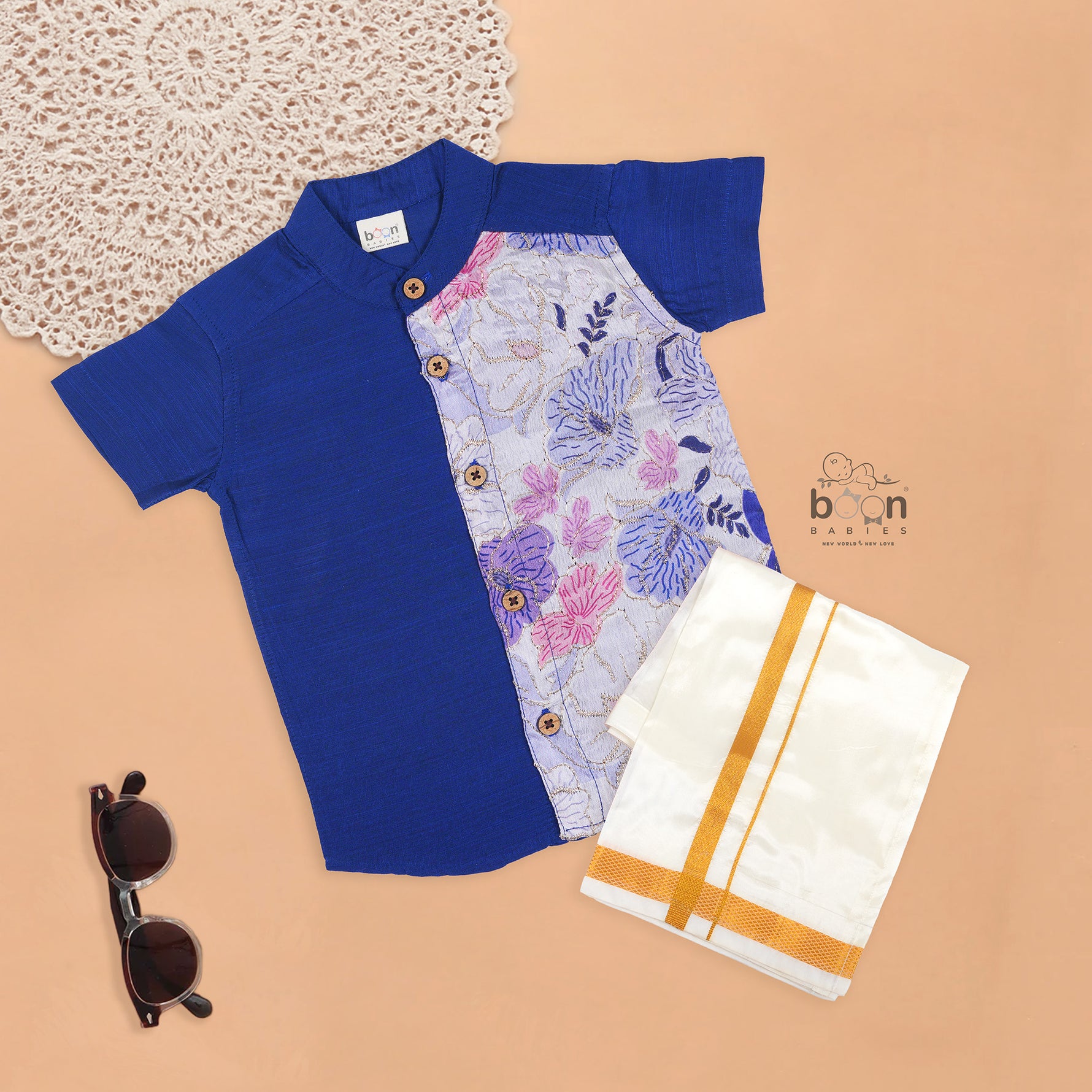 Royal blue silk panel shirt with floral embroidery paired with white pattu dhoti featuring a gold border – traditional festive outfit for boys by Boon Babies.
