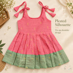 Coral pink tissue silk cotton baby girl knot frock front view with tie-up shoulders, pleated skirt and sage green border