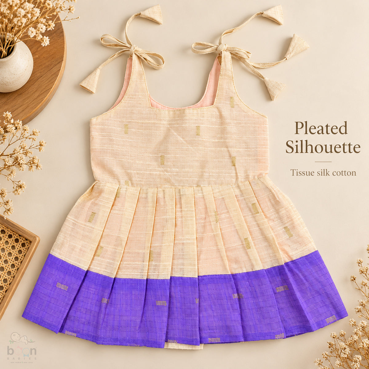 Cream tissue silk cotton baby girl knot frock front view with tie-up shoulders, pleated skirt and purple border