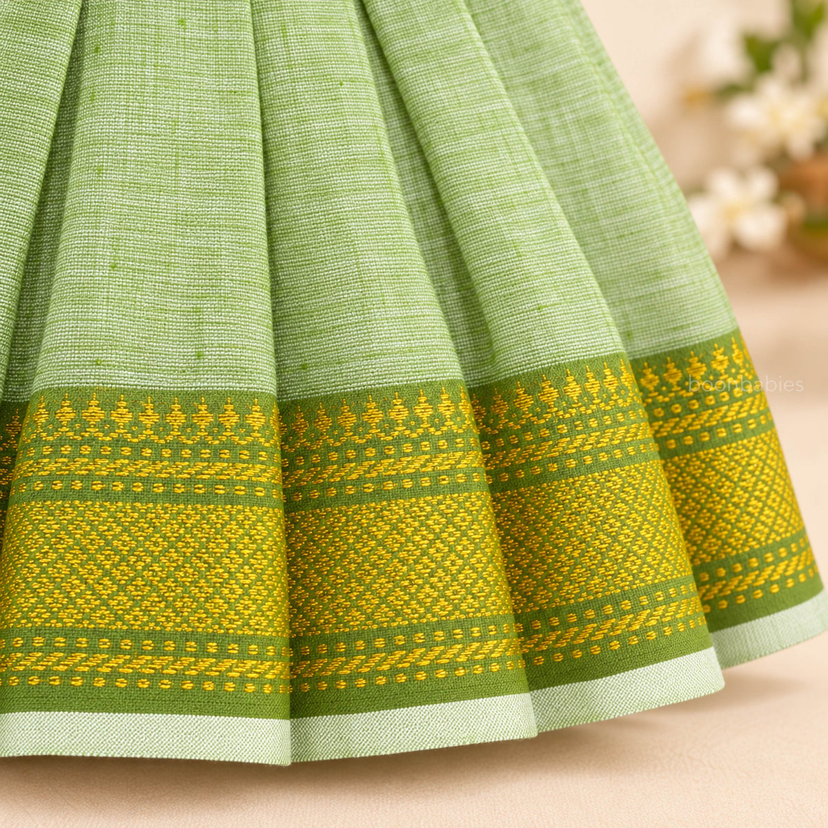Traditional green and yellow woven hem border detail on pastel green Mangalagiri cotton baby girl frock